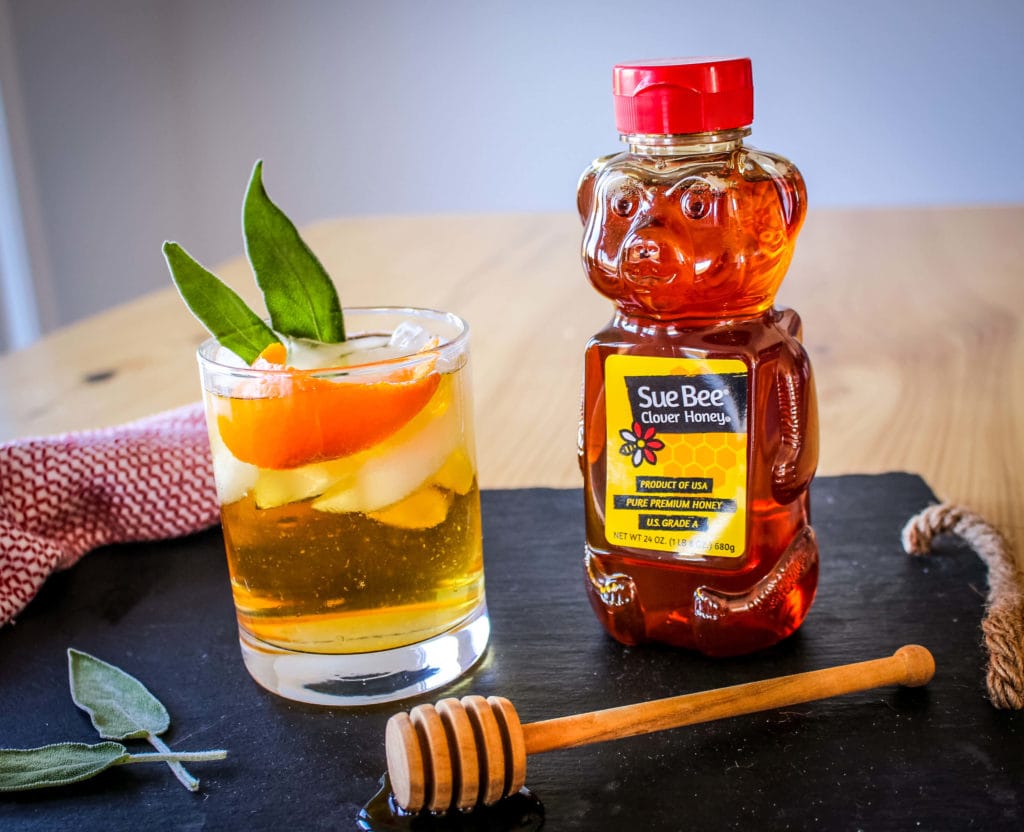 Photo of Sue Bee® honey and a drink with sage leaves.