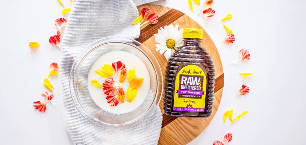 Photo of flower petals in milk and Aunt Sue's Raw & Unfiltered Honey
